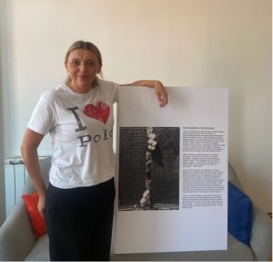 Irena steht neben einem Plakat der Ausstellung "Recognize the signs"